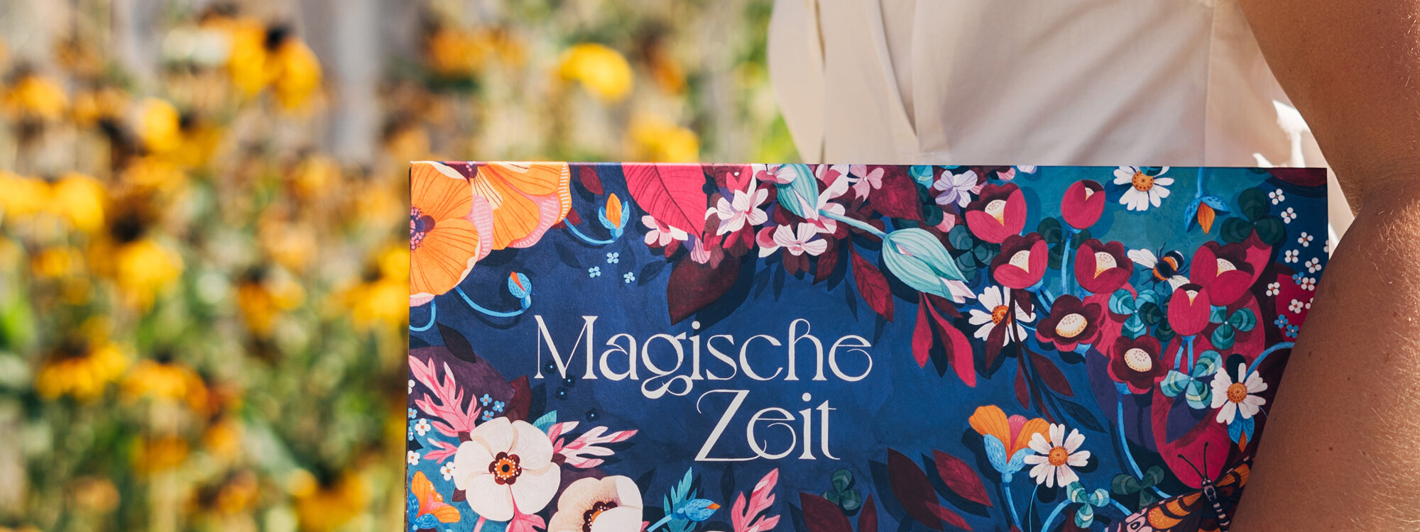 Schachtel des Bio-Saatgut-Adventskalenders „Magische Zeit“ Wilder Blütenrausch vor gelben Sommerblumen